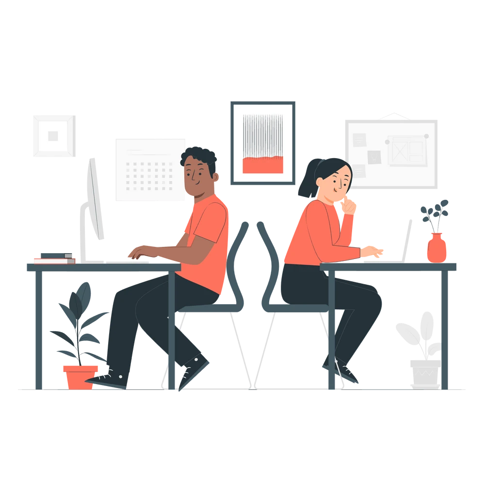  Two individuals in a workspace setting, each engaged with their respective computers.